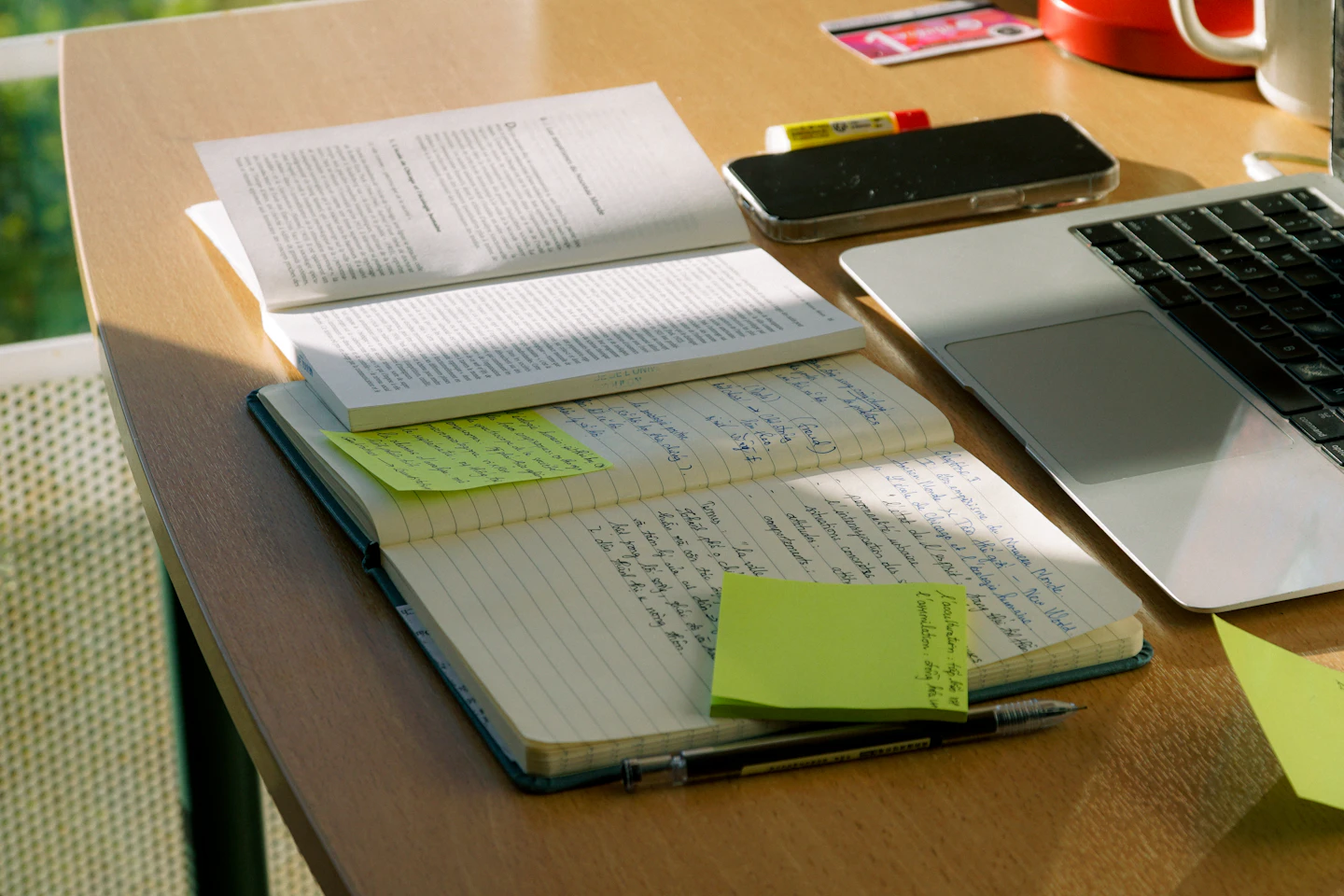 Open reference material and handwritten notes beside a laptop.