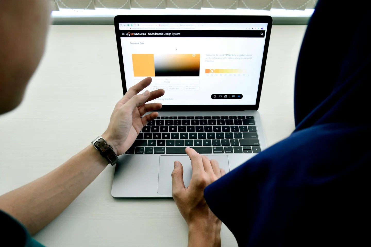 A person reviewing a digital interface on a laptop at a working desk.