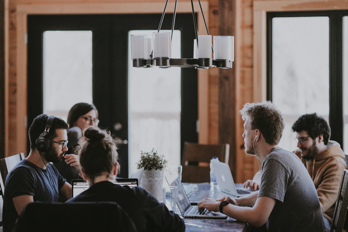 A team working together around a shared table in a brick-walled office.