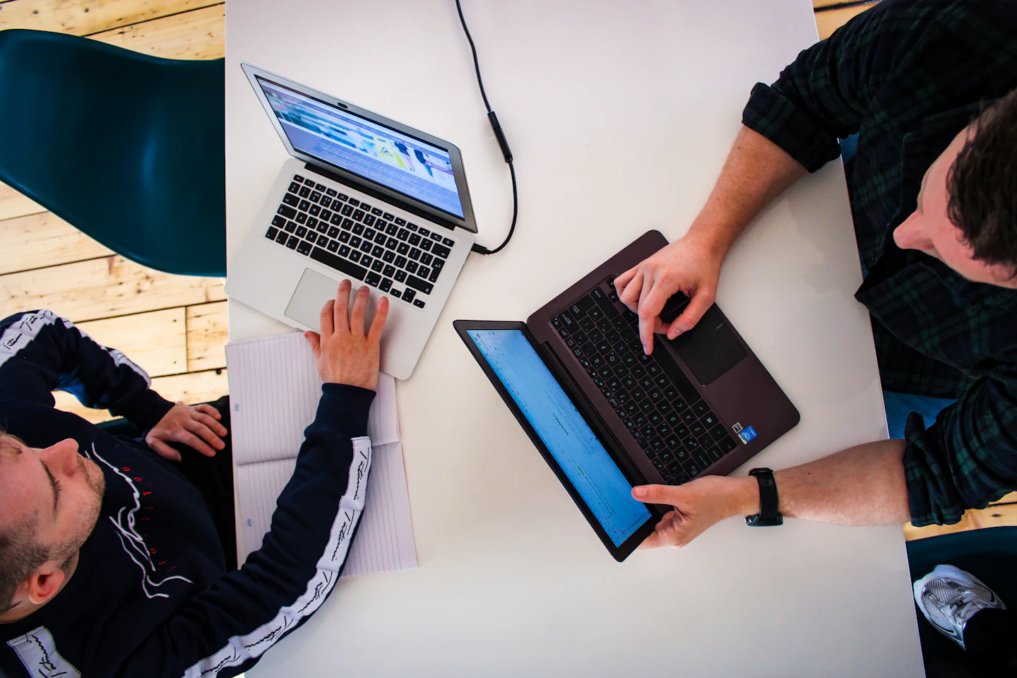 Two colleagues reviewing work on laptops at an office table.