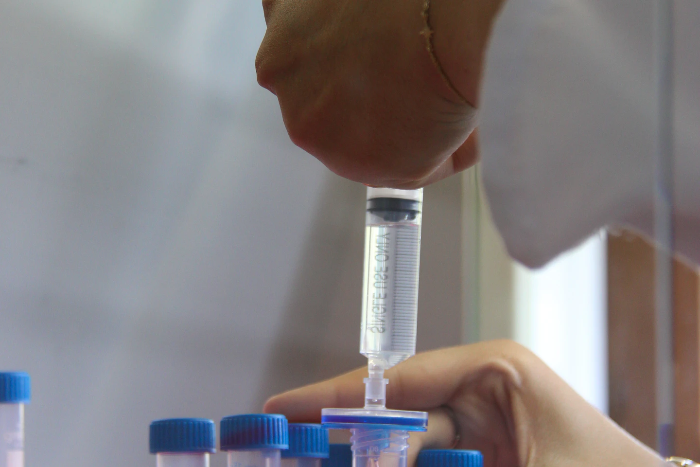 A laboratory technician transferring liquid into sample tubes.