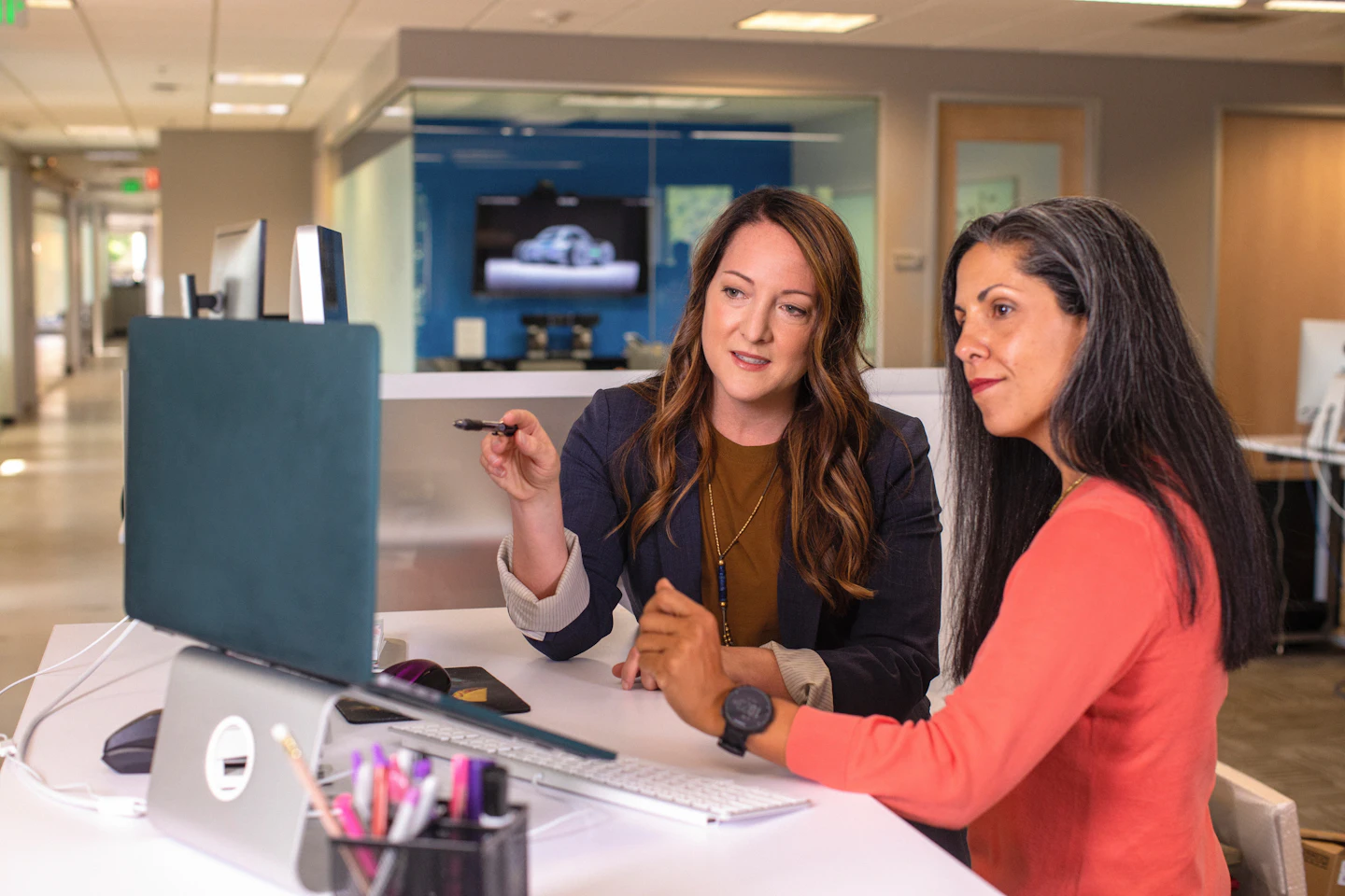 Two colleagues examining a laptop screen and discussing their notes.