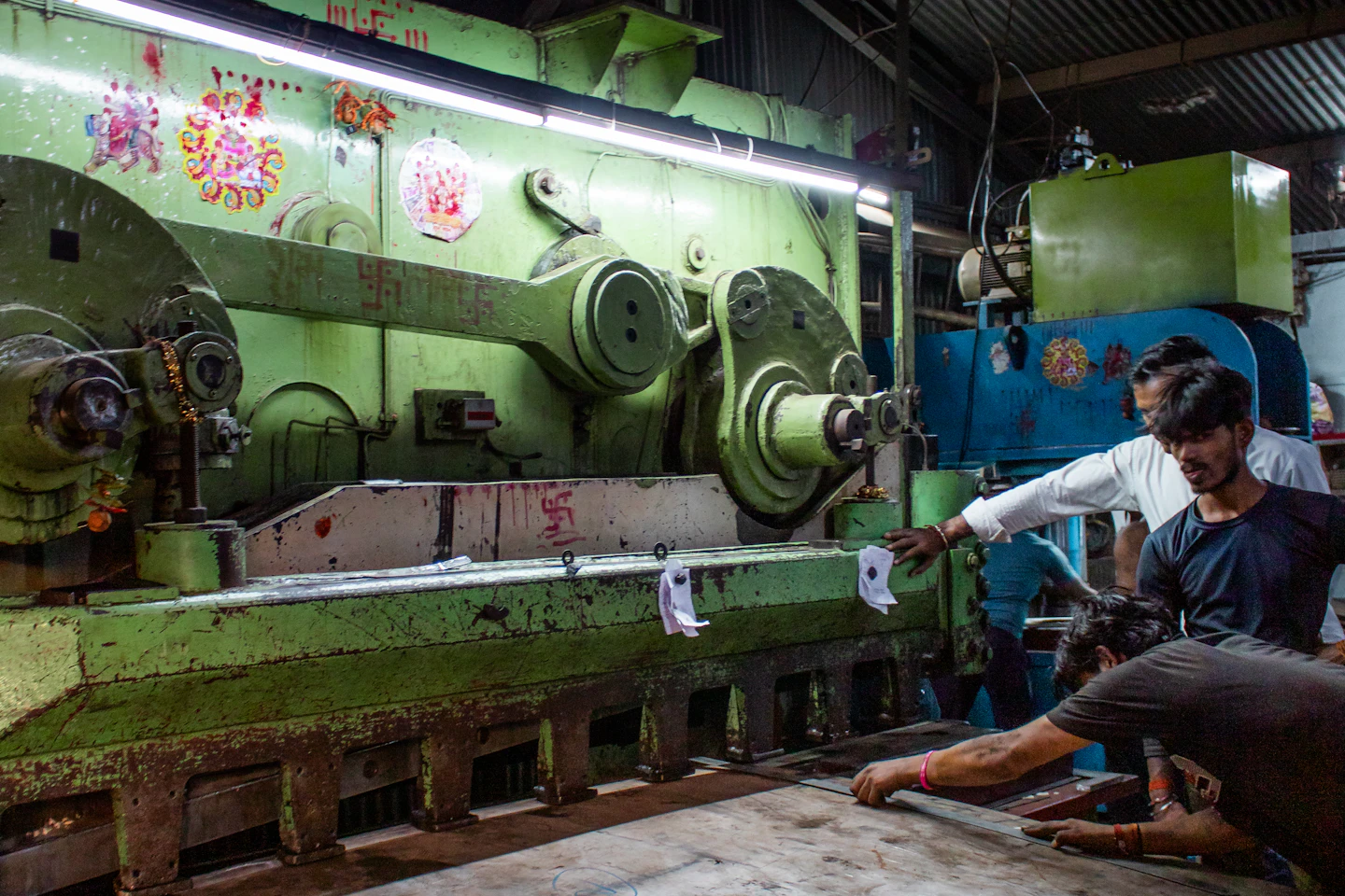 Workers measuring and cutting metal together in a working factory.